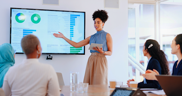 A banking executive presents AI adoption data on a screen to colleagues in a boardroom meeting.