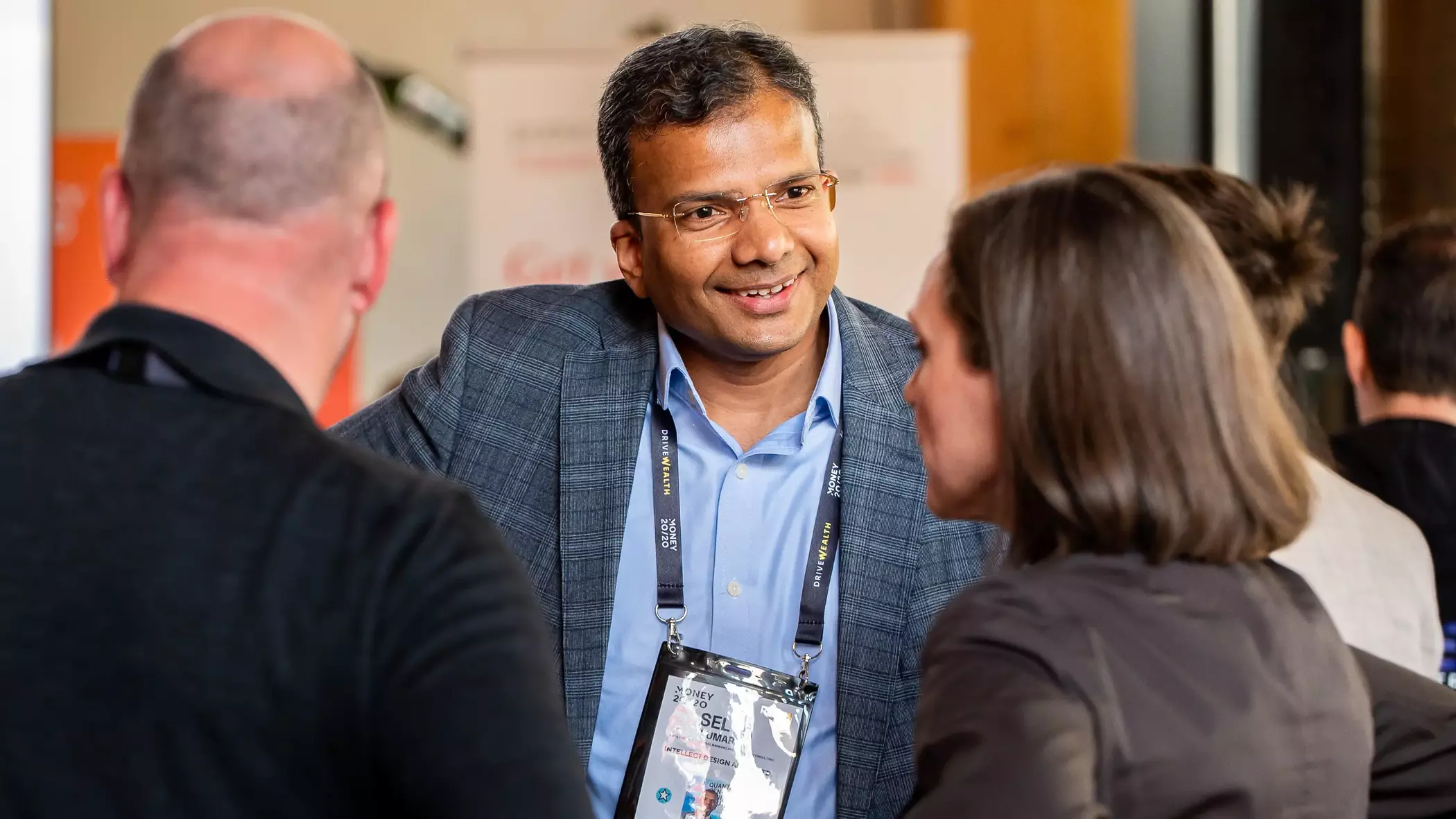 Three happy, professional-looking individuals wearing Money2020 delegate badges, engaged in conversation.