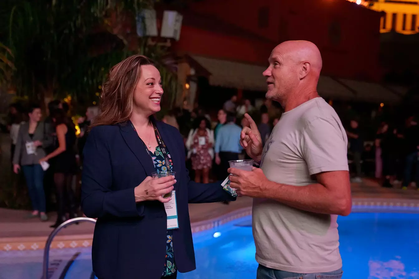 A man and a woman have a discussion by a swimming pool at Money20/20