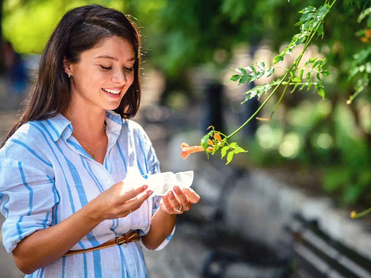 Types of Allergy Medicine Woman in a park with a tissue in hand