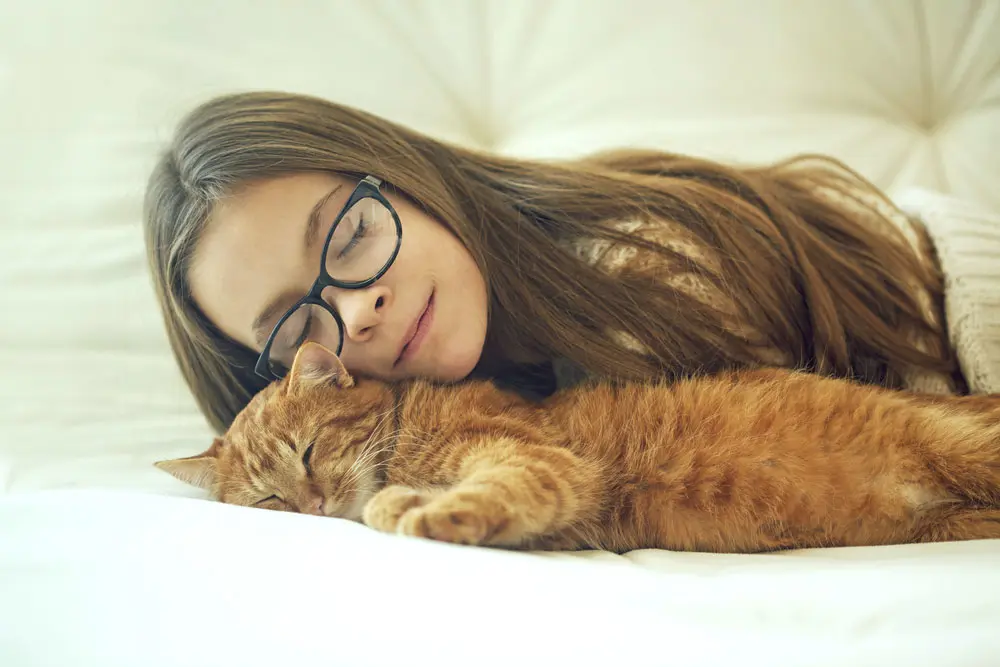 Girl laying in bed with her pet cat
