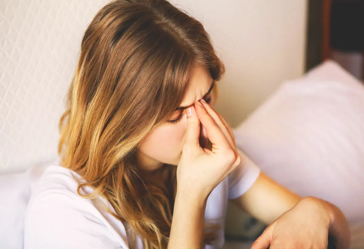 Cold vs Allergies Woman rubbing her nose to relieve headache