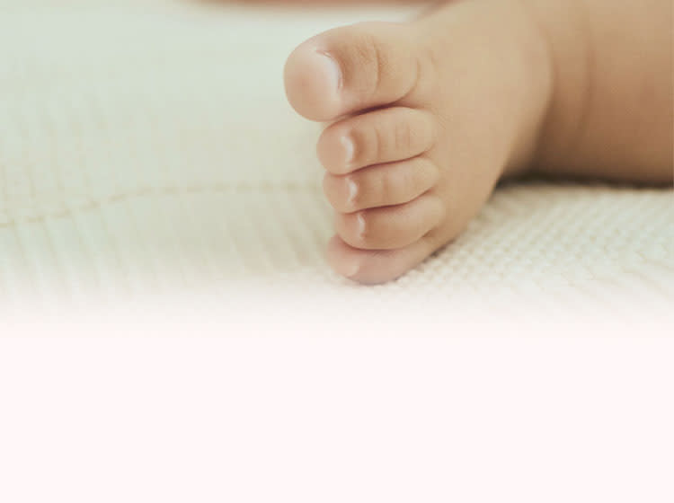 Baby lies on a blanket with the feet in focus