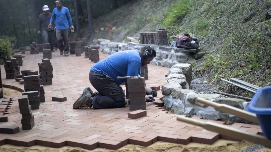 Local paver contractors installing a paving stone courtyard in backyard 