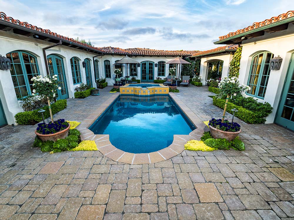 Paver pool deck in-ground pool with paving stone coping in Mediterranean courtyard