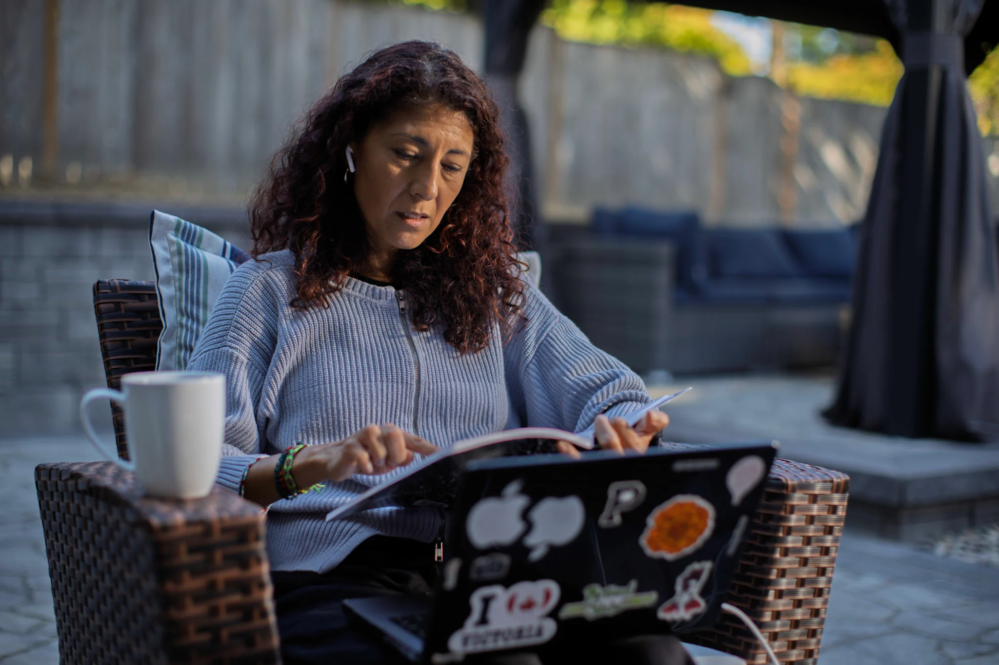 Woman working on computer outdoors in sunshine on paver patio