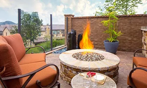 Fire pit, gas fire pit, lit, circular fire pit, pavers, paver patio, water fountain, retaining wall, patio furniture, paving stones, cheese plate, universal region, daytime