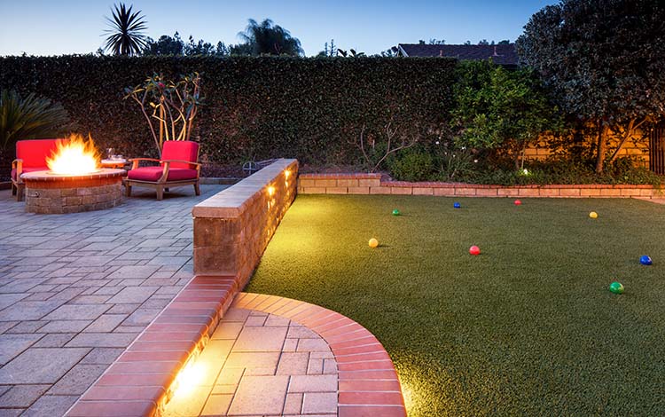 Outdoor lighting, fire pit, fire, paver patio, pavers, artificial turf retaining wall, bocce ball, outdoor games, patio furniture, artificial grass, California, evening