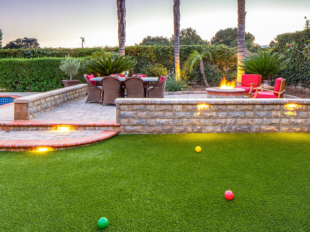 Paver patio with turf and steps with lighting 