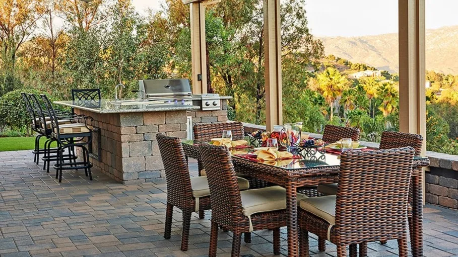 Outdoor dining table set for fall holiday entertaining in an outdoor kitchen with grill