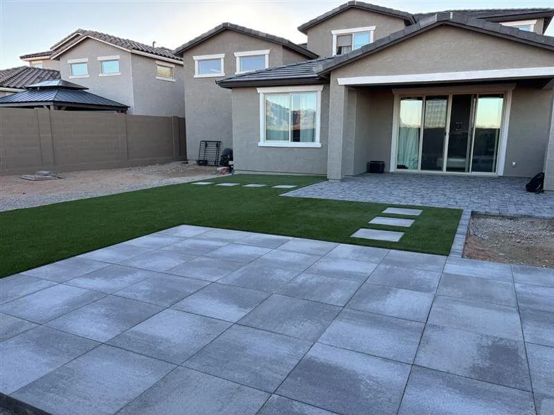 A large backyard remodel with patio pavers and artificial turf