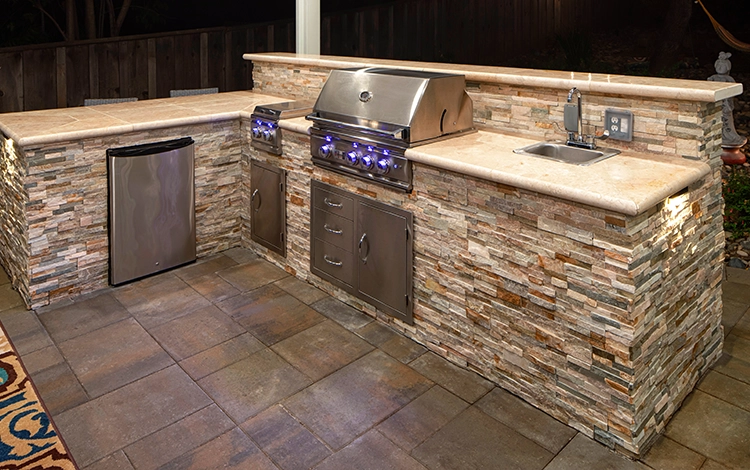 Outdoor stone kitchen with grill, cabinets, sink and more