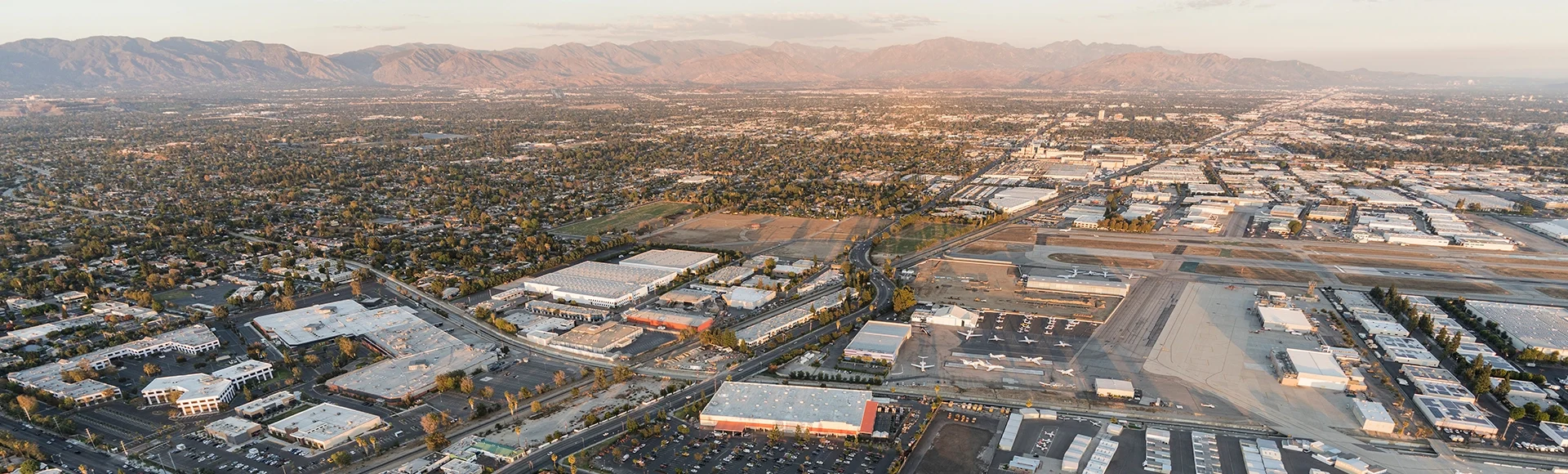 Late afternoon aerial view of homes, industrial buildings, tarmac and runway at Van Nuys airport in the San Fernando Valley.