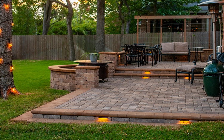 Paving stone raised patio with stone wall and built-in lighting.