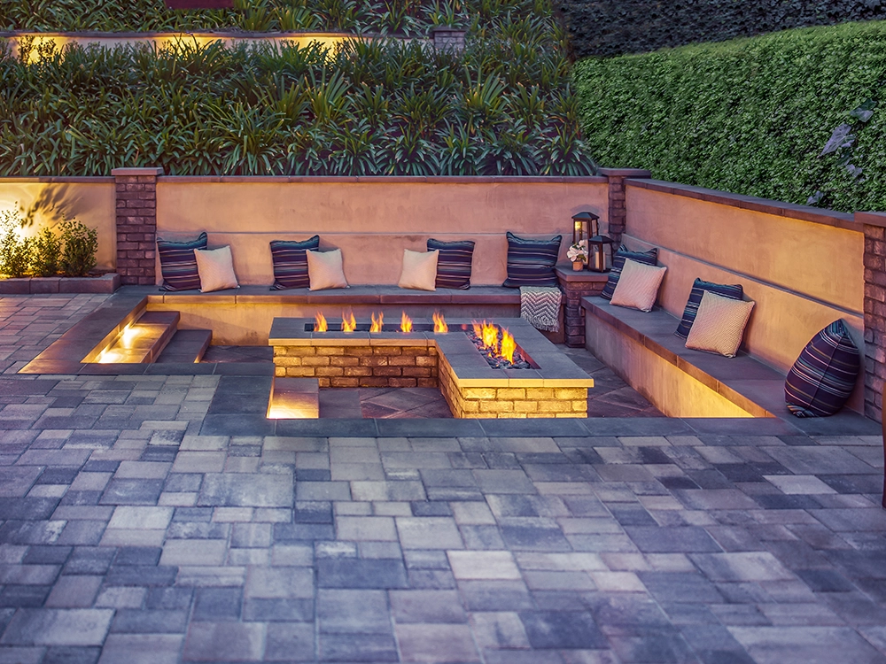 Set in fire pit made of paver stones with bench and patio. 