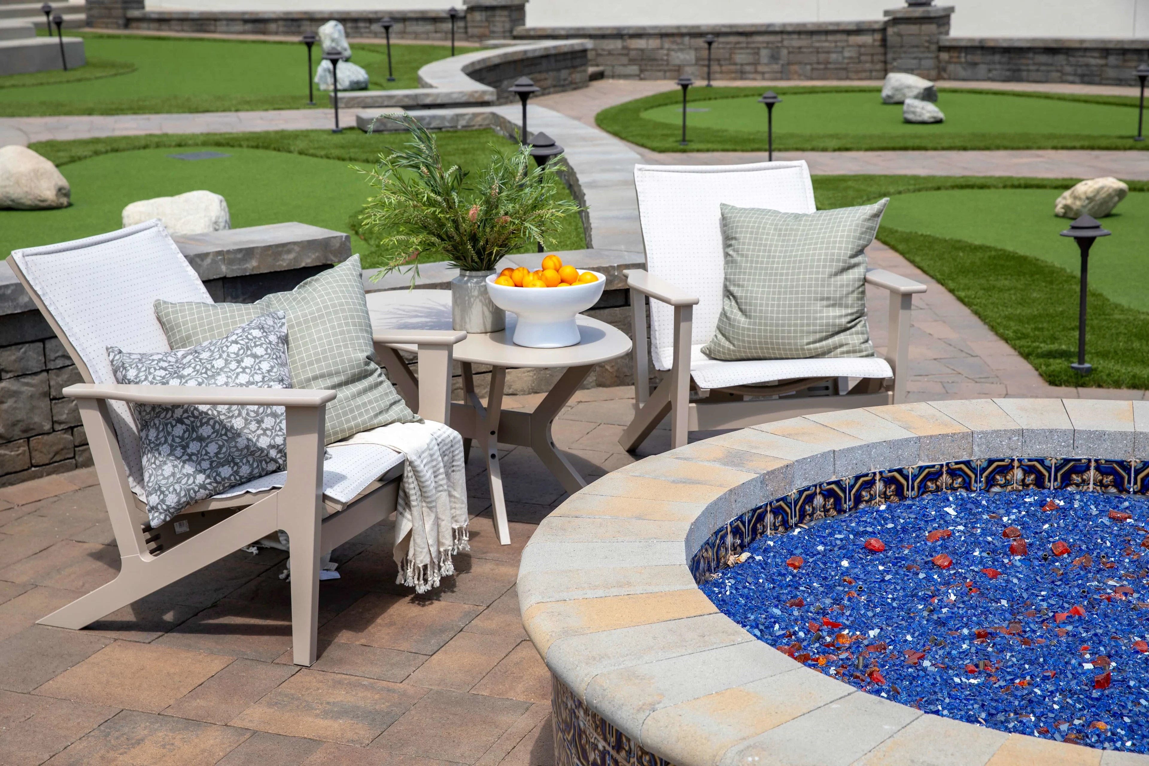 Seating by modern fire pit with turf putting green in the background