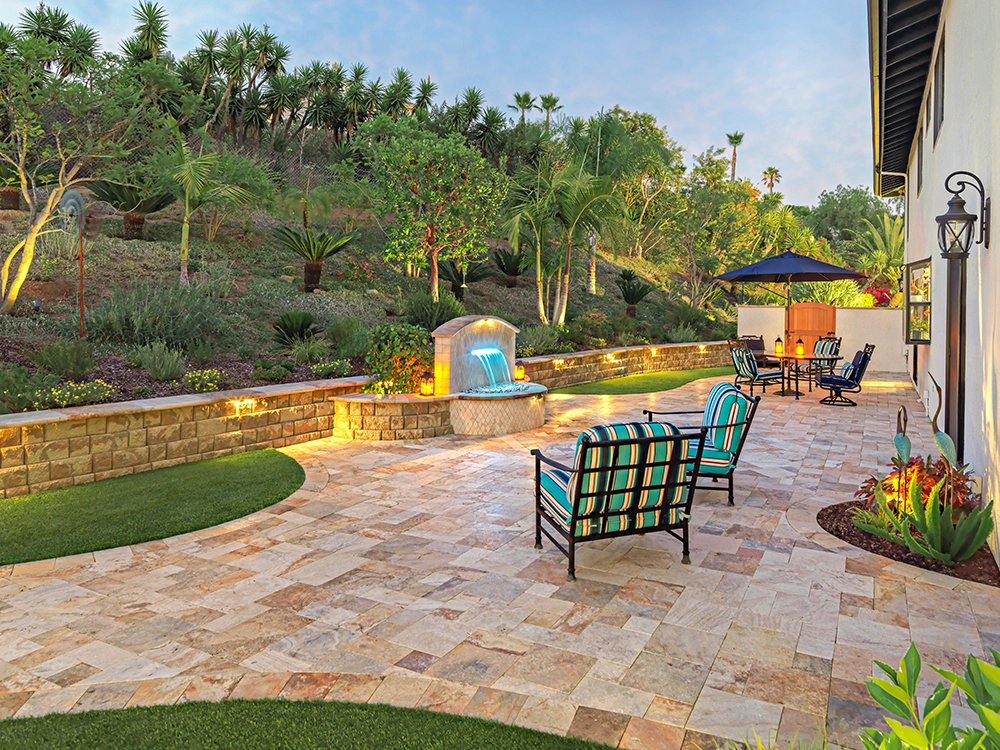 Small backyard paver patio with paver wall and cool water feature. 
