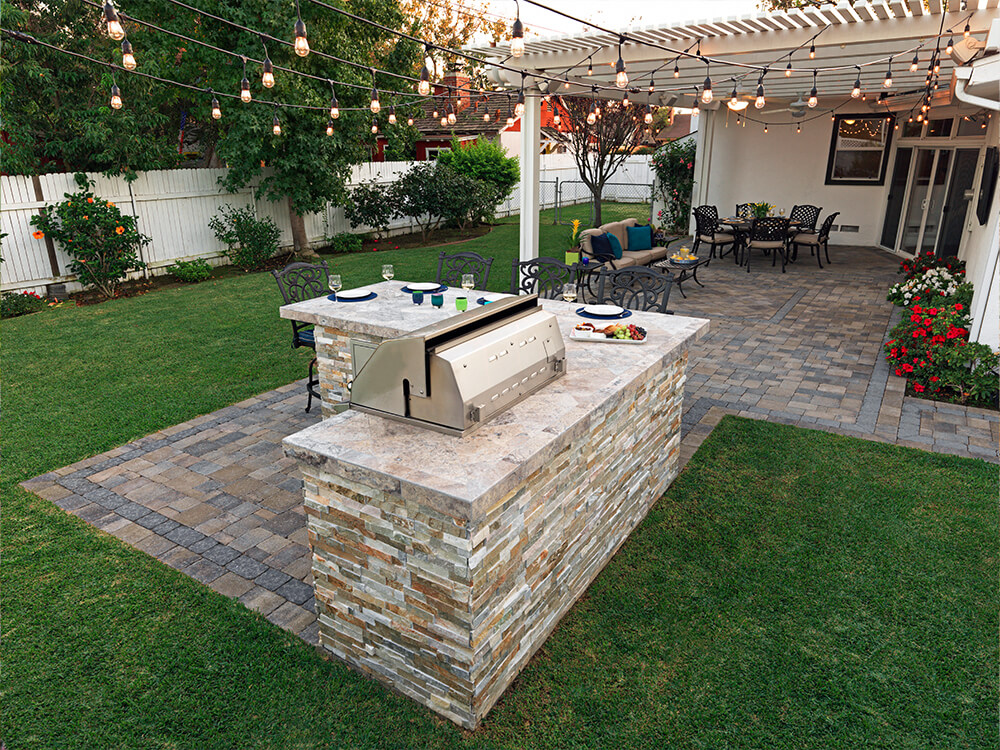 California backyard with stone patio and outdoor BBQ with pergola and turf lawn 
