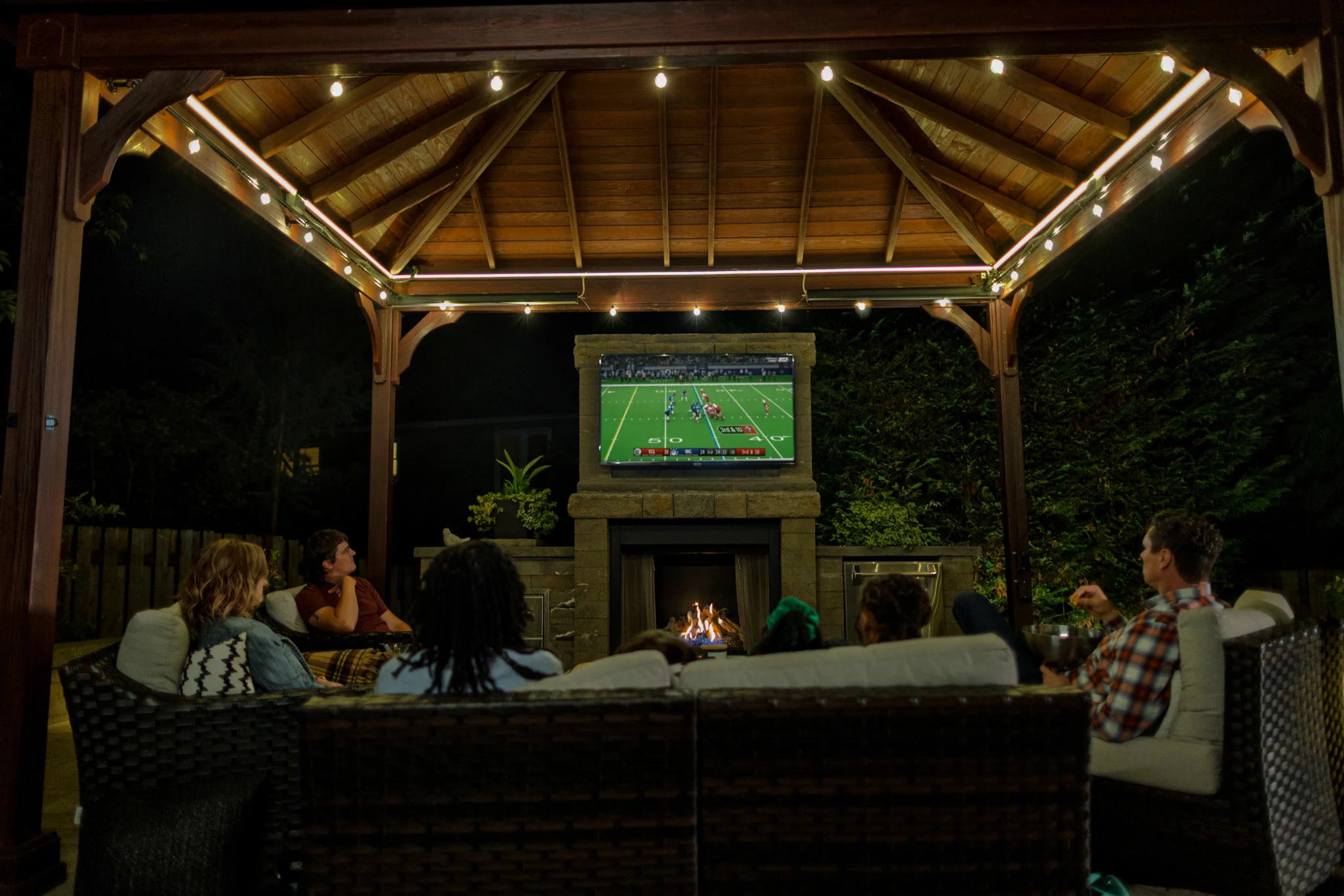 Friend watching football on outdoor television under pergola