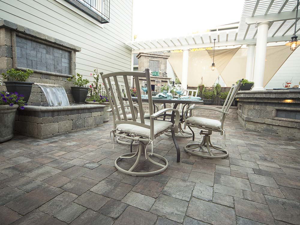 Paver patio with water fountain feature, pergola, dining area, and outdoor fireplace