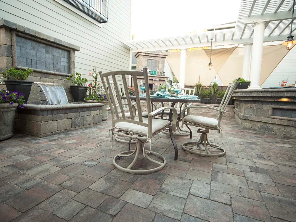 Paver patio with water fountain feature, pergola, dining area, and outdoor fireplace