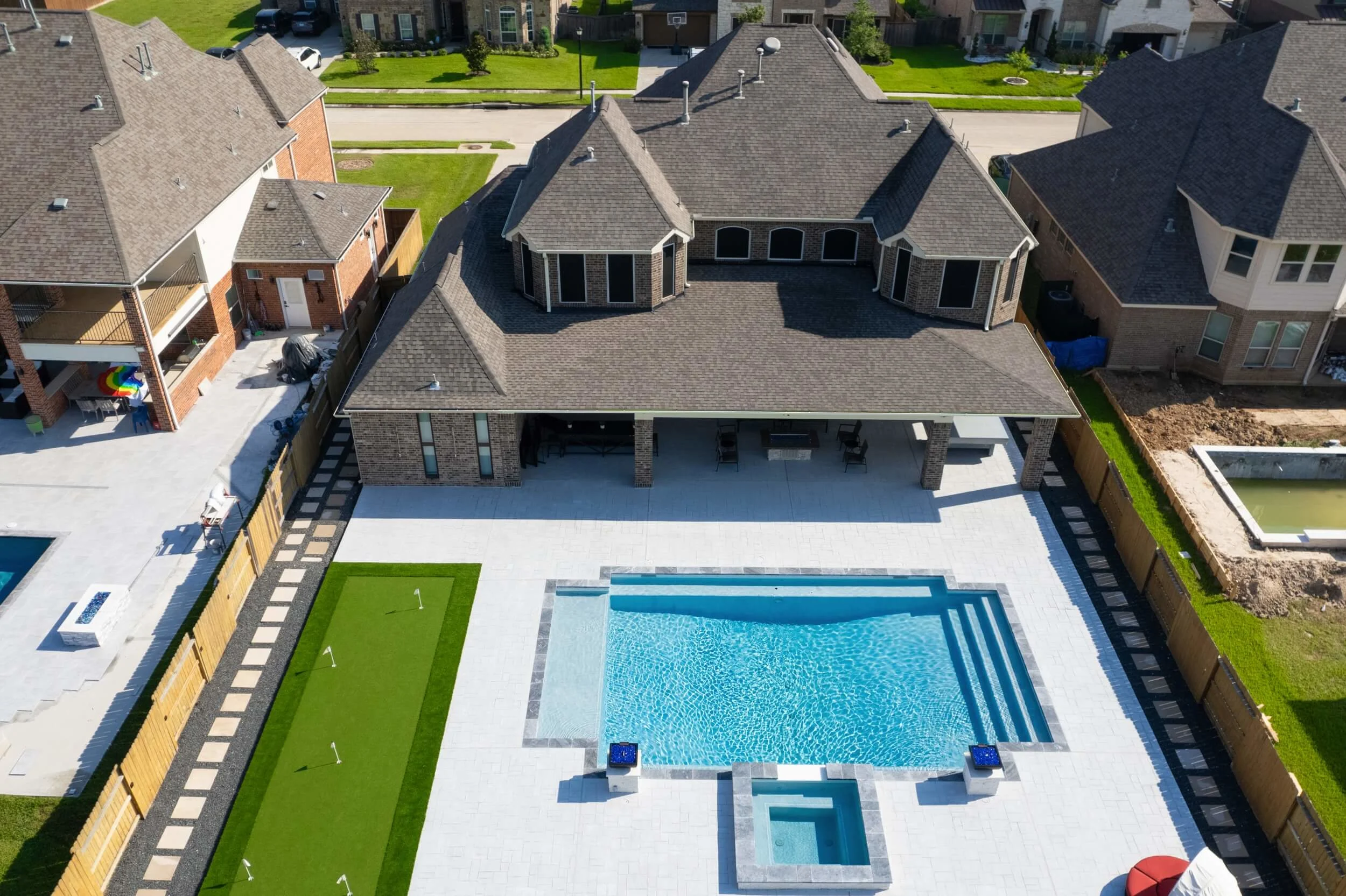 Aerial overview of Houston backyard remodel with artificial turf putting green by the pool and paver walkways