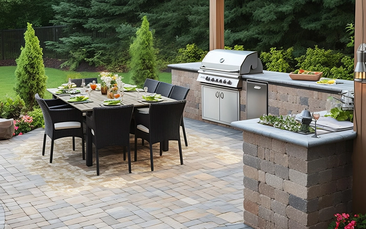 Outdoor stone kitchen on a paving stone patio with built-in grill, fridge, wine cooler