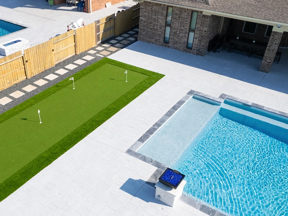 Texas backyard with putting green and paver pool deck. 