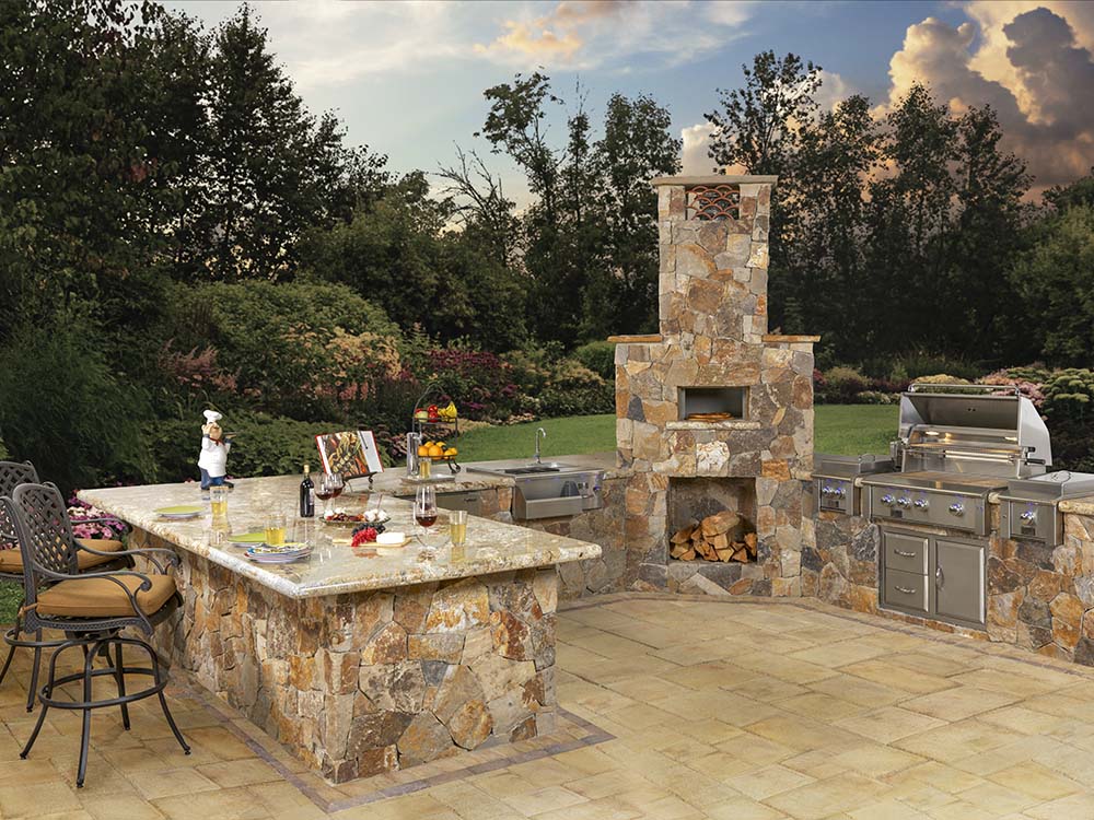 Stone kitchen with paver patio and bar with built-in fire pit, pizza oven, and grill