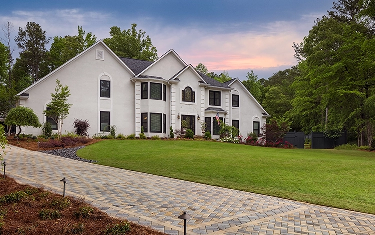 Large white home with paving stone driveway