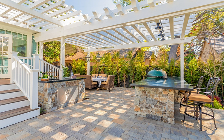 Lovely backyard haven with pergola and paving stone patio with outdoor kitchen