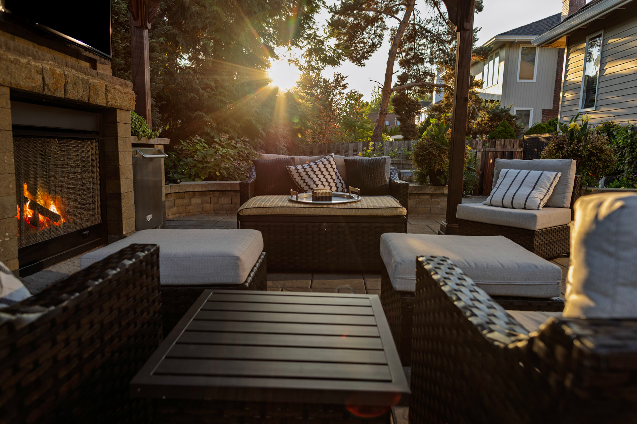 Outdoor fireplace under a pergola as the sun sets