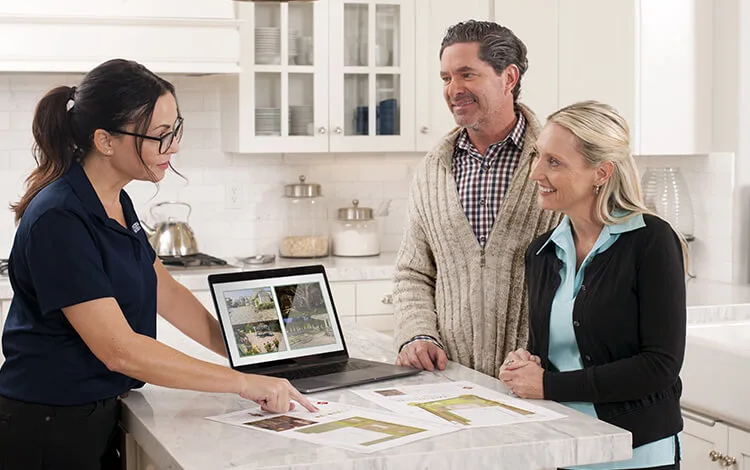 System Pavers design consultation at a home. One employee with a laptop and two homeowners. 