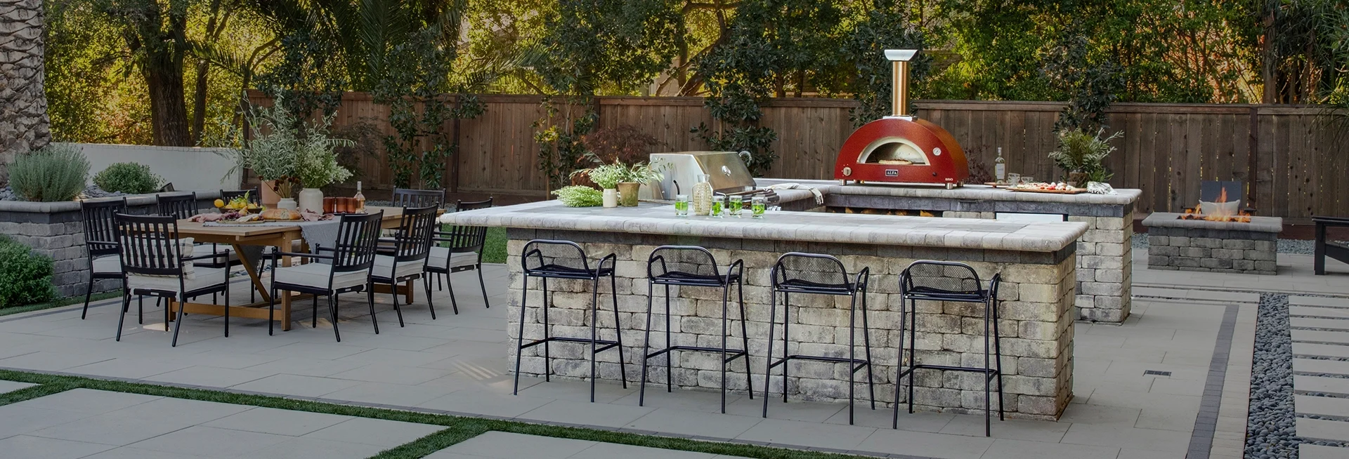 Outdoor kitchen with pizza oven, grill and paving stone bar