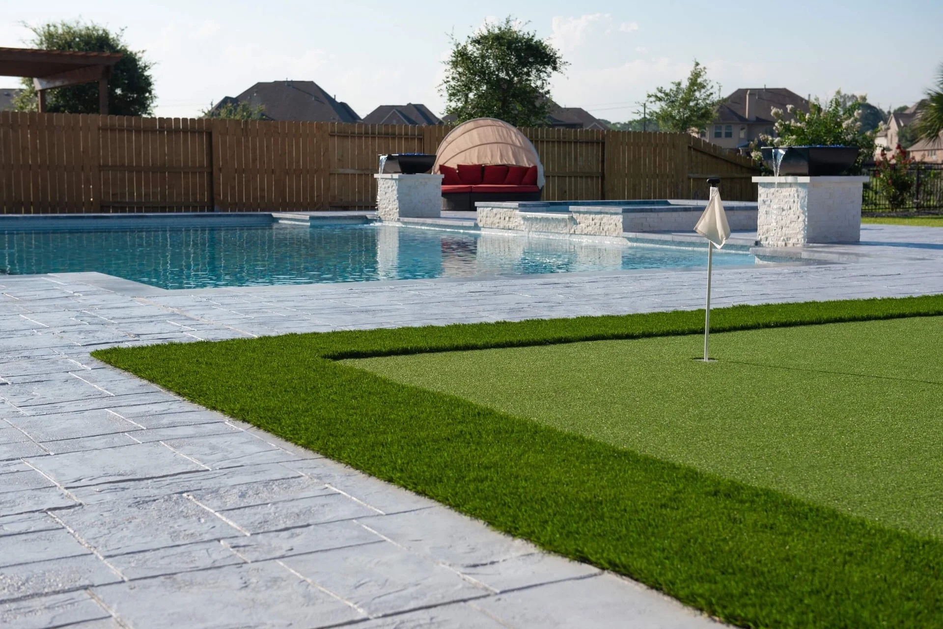 Paver and turf outdoor remodel in Houston Texas backyard with golf putting green and pool deck