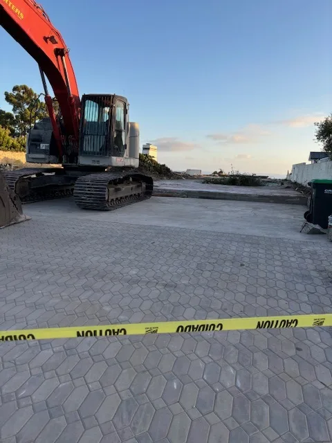 Paving stone driveway with construction equipment outlasts demolished house