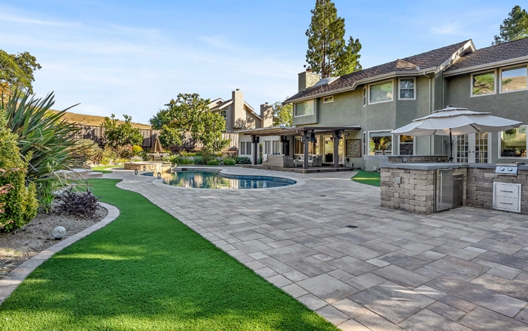 Backyard with paver pool deck, outdoor kitchen, artificial turf and pergola patio deck. 