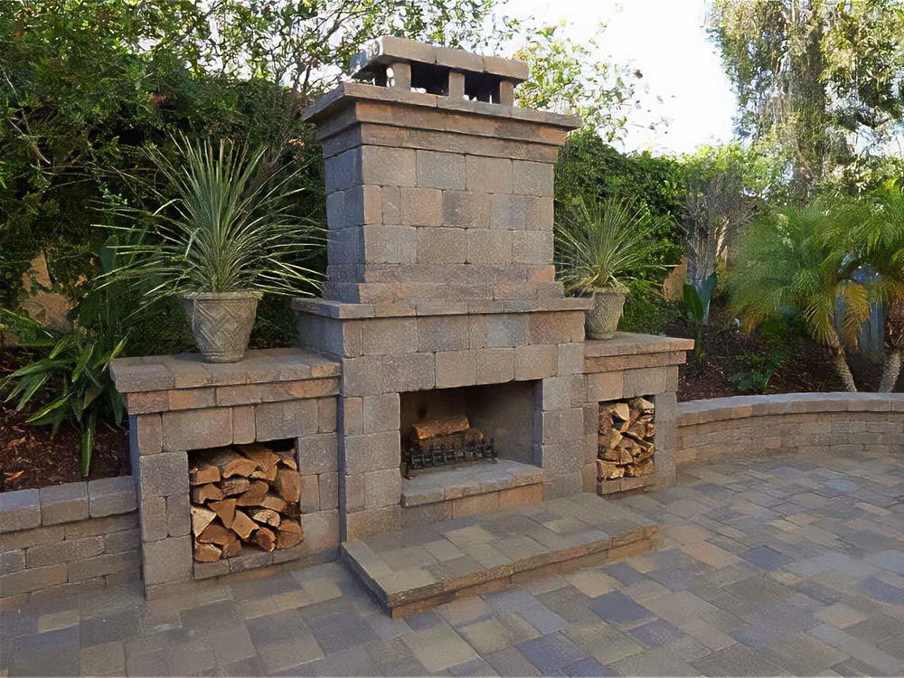 Outdoor fireplace, paver patio, retaining wall, wood, wood-burning fireplace, outdoor living, backyard, paving stones, California, daytime