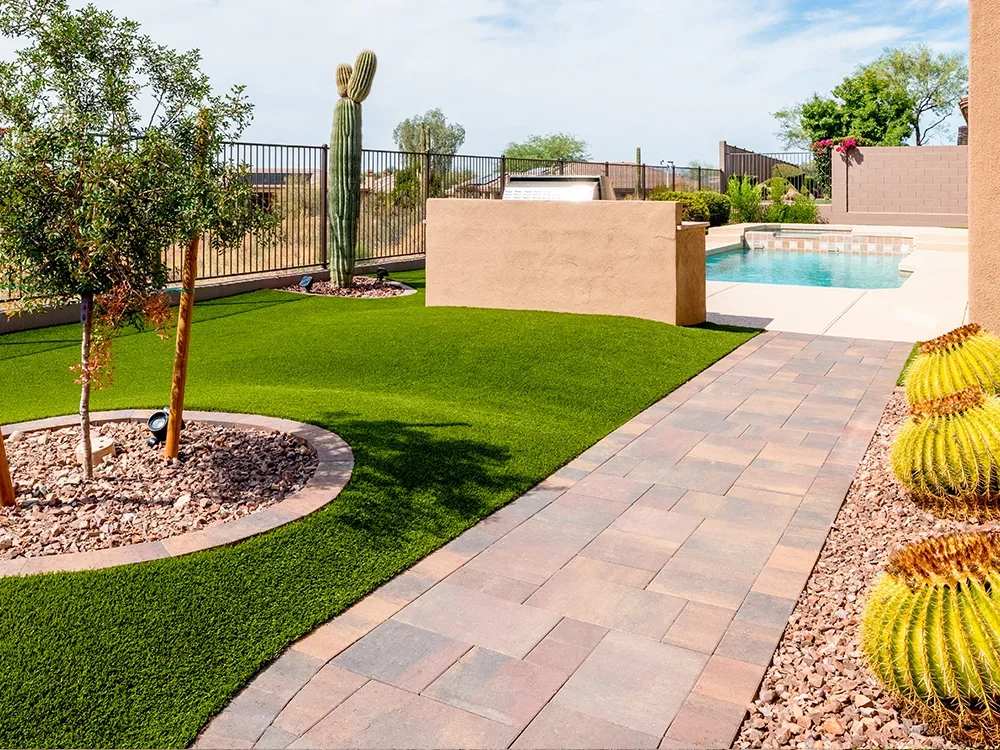 Backyard paver path with artificial turf lawn.