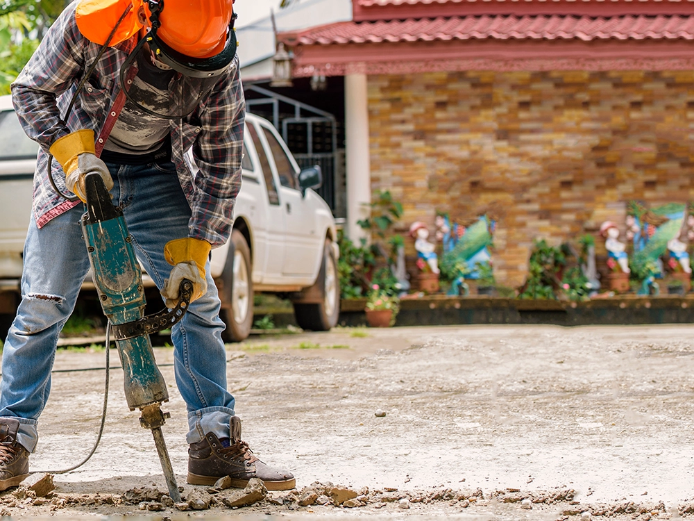 Man with a jackhammer destroys a driveway. 