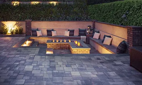 Fire pit, gas fire pit, lit, L-shaped fire pit, sunken fire pit, outdoor lighting, pavers, paver patio, patio furniture, retaining wall, paving stones, universal region, night