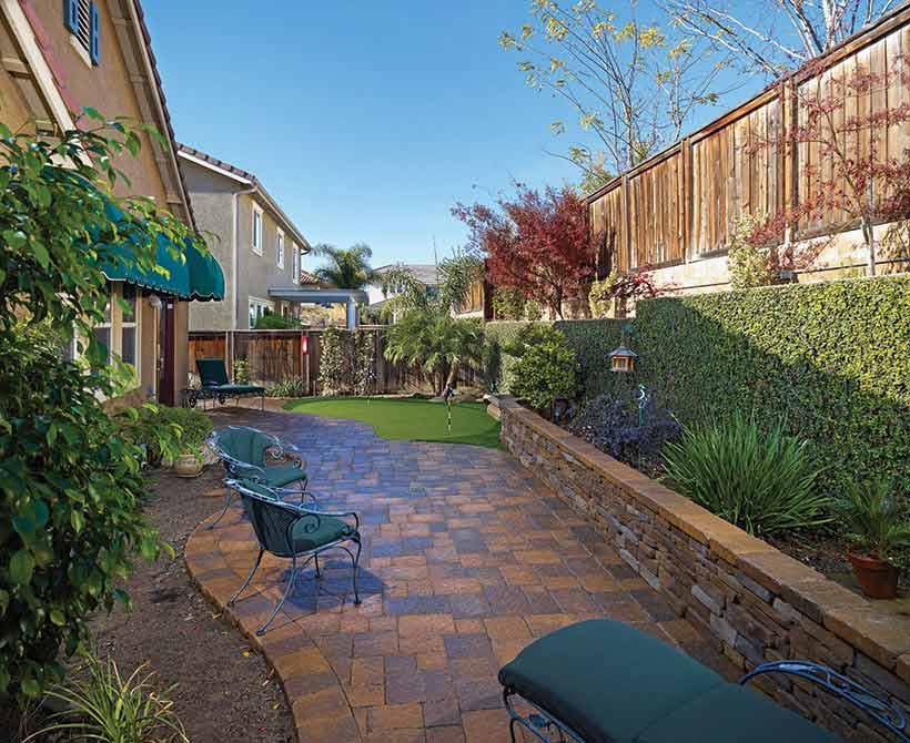backyard with pavers with retaining wall and putting green