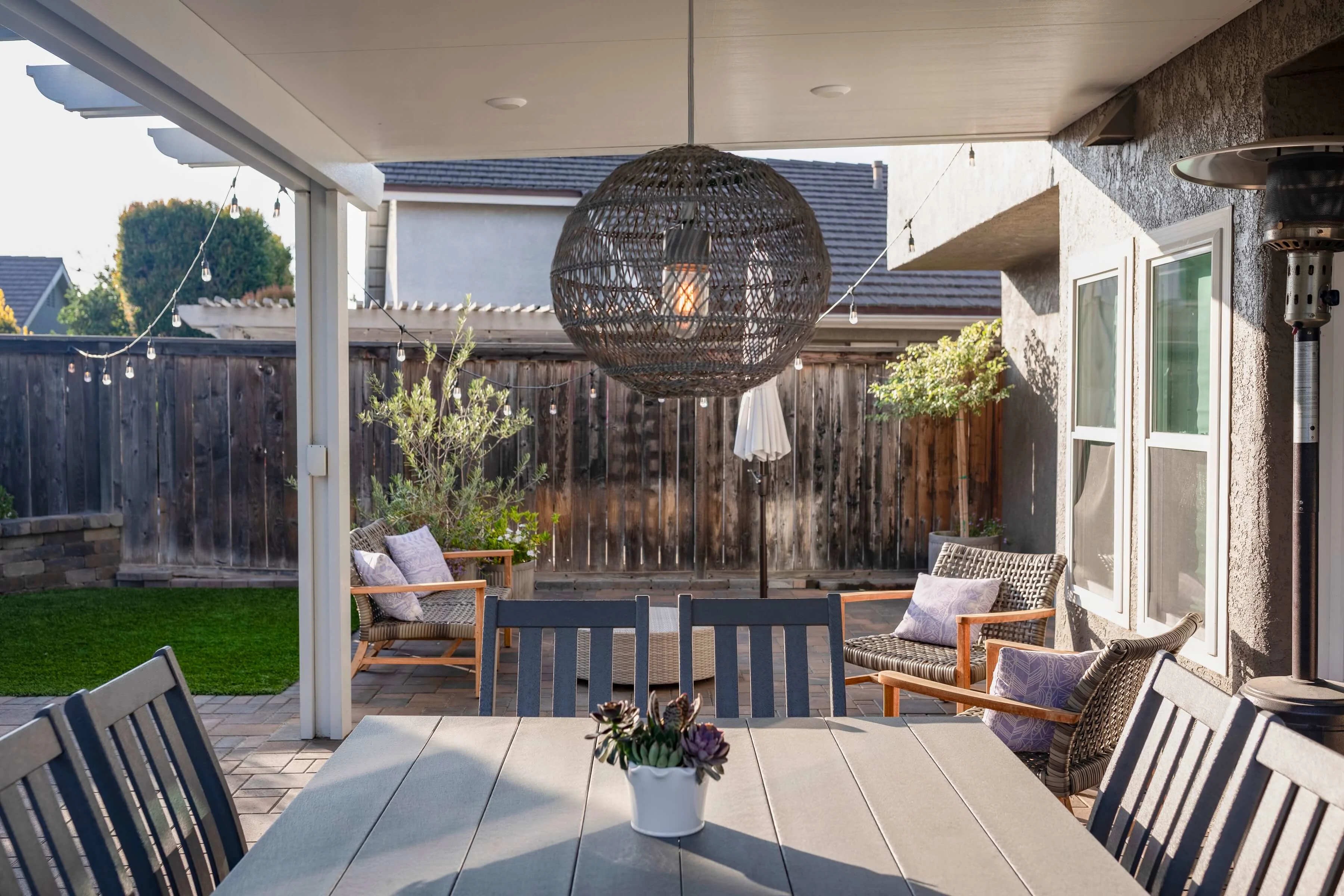 Pergola covered paver patio with dining table and outdoor seating 