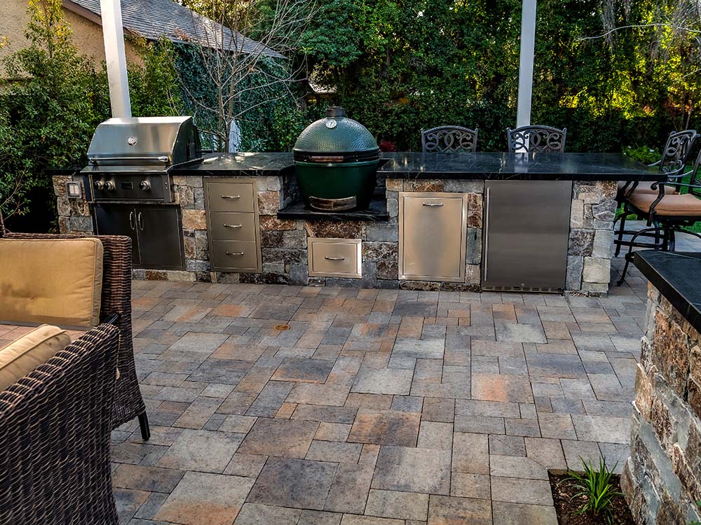 Built-in outdoor kitchen on paver patio with green egg grill