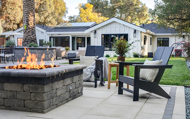 Paving stone fire pit on a paver patio with chairs. 