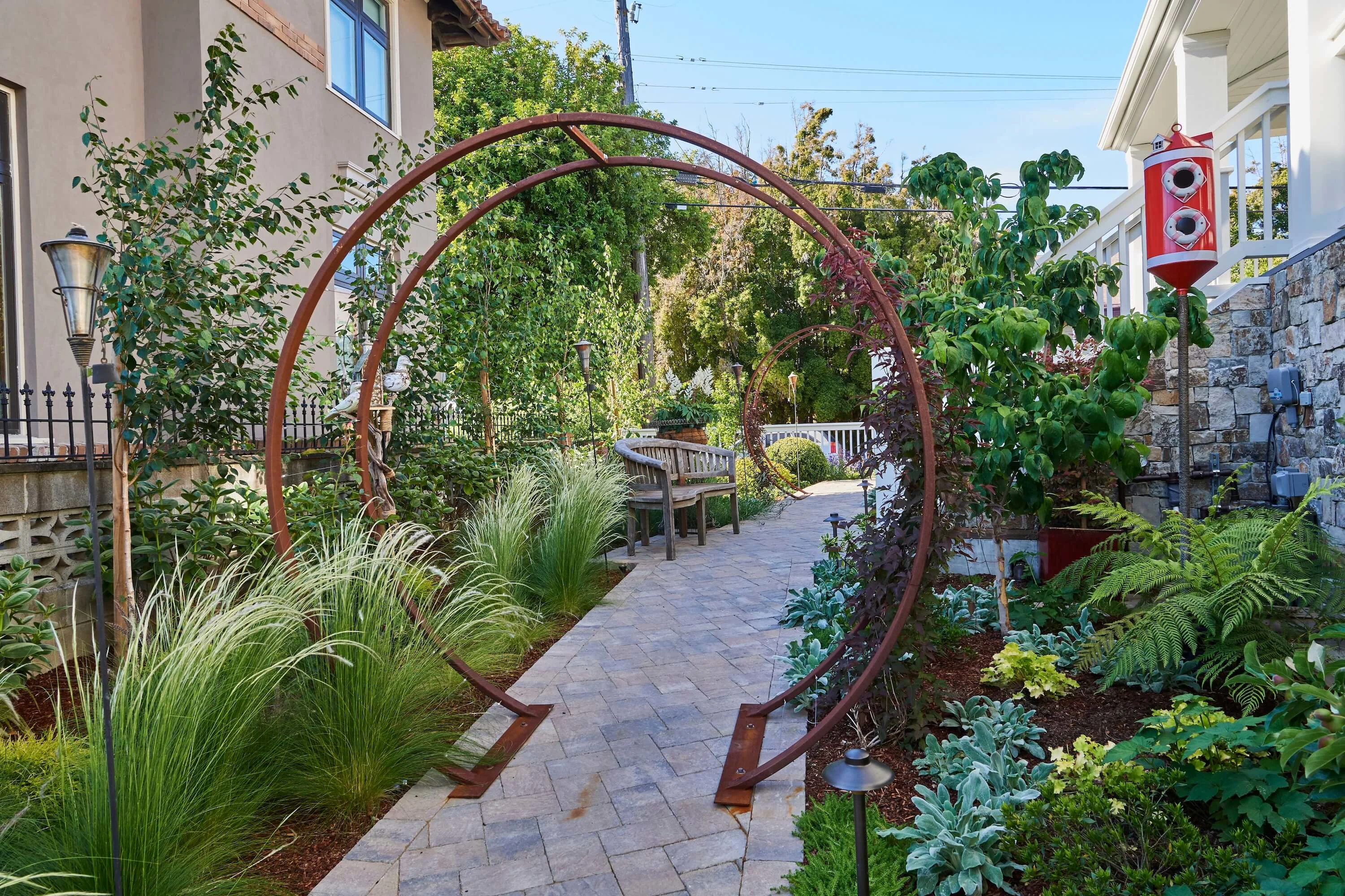 Outdoor Garden Space With Paver Walkway and Curved Trellis Tunnels 