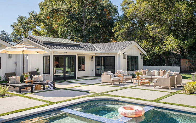 Lovely backyard with seating area on a paver patio and pool deck.