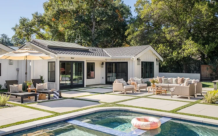 Lovely backyard with seating area on a paver patio and pool deck.