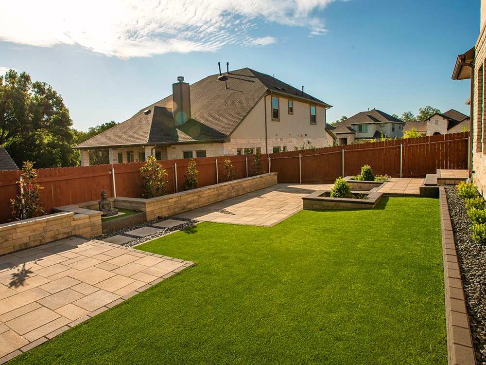 Artificial turf lawn with paver patio inserts and paver planters. 