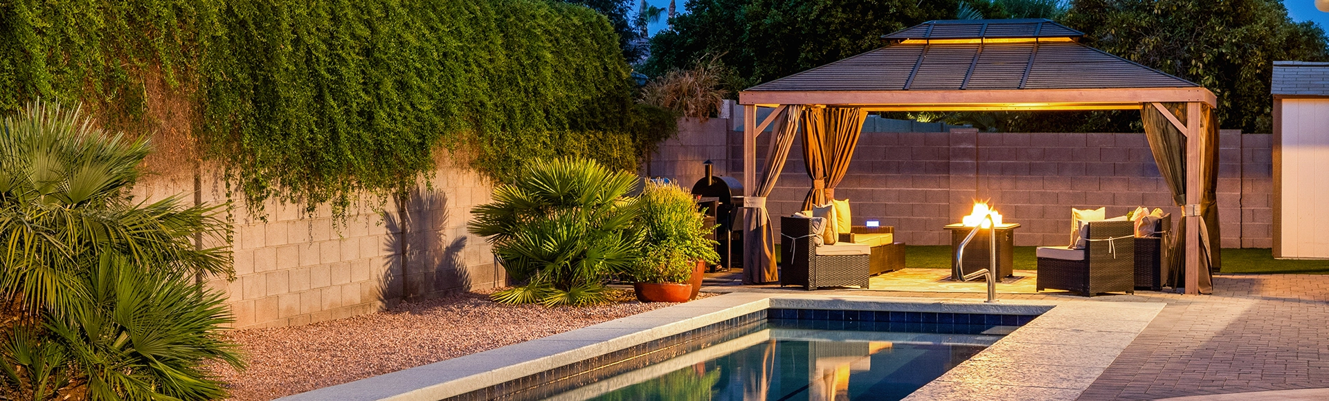 Bright pergola at night by a paving stone wall and patio. 